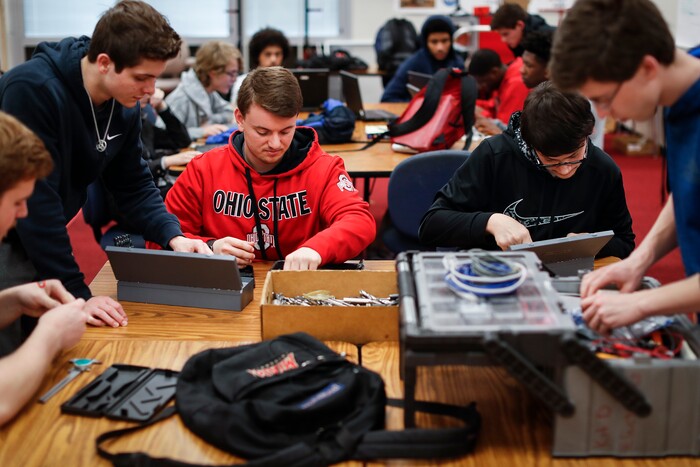 In this March 7, 2017 photo, Colerain High School students in Cincinnati huddle in groups to design and build a robot for the FIRST Robotics competition. The international contest draws corporate sponsors looking to recruit students interested in engineering, software development, and technology design careers. (AP Photo/John Minchillo)