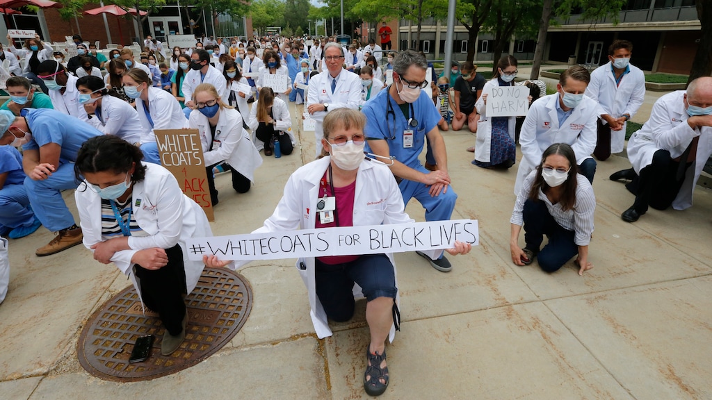 Healthcare workers and medical students pause for 8 minutes 46 seconds of silence in front of the University of Utah Health Sciences Education Building during a demonstration in support of the Black Lives Matter movement Friday, June 5, 2020, in Salt Lake City. The White Coats for Black Lives protest was organized to stand in solidarity with those speaking out against the death of George Floyd who died after being restrained by Minneapolis police officers on May 25. (AP Photo/Rick Bowmer)