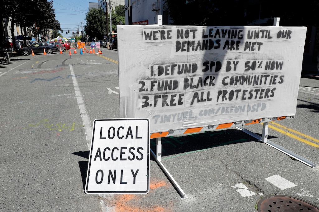 (Ted S. Warren | AP) A sign on a street barricade lists some of the demands of protesters in what has been named the Capitol Hill Occupied Protest zone in Seattle, Monday, June 22, 2020. For the second time in less than 48 hours, there was a shooting near the "CHOP" area that has been occupied by protesters after Seattle Police pulled back from several blocks of the city's Capitol Hill neighborhood near the Police Department's East Precinct building.
