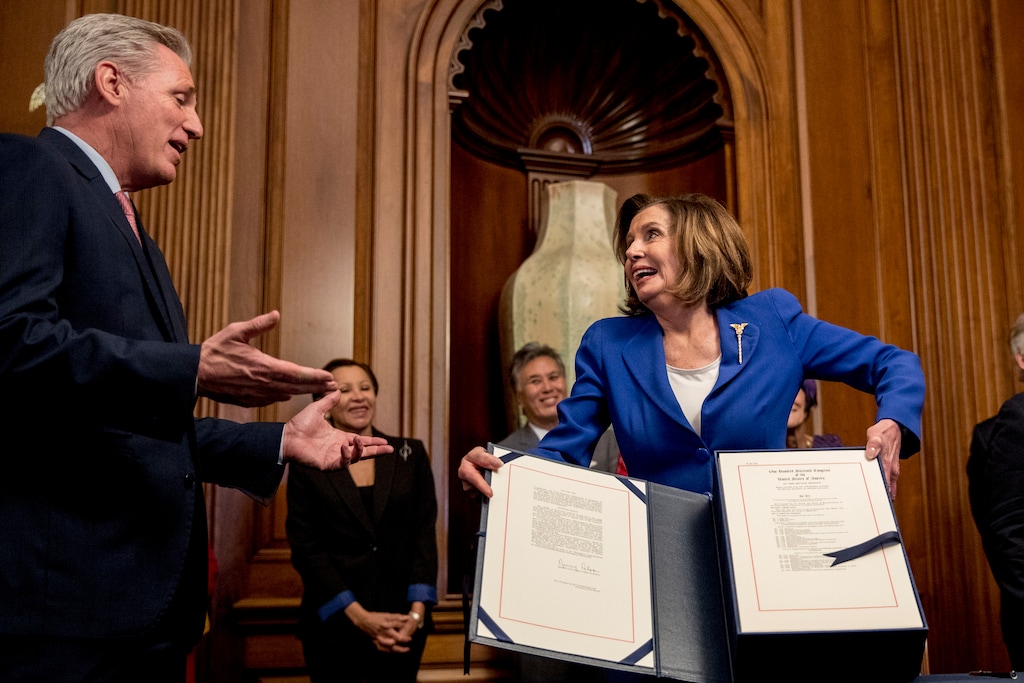 (Andrew Harnik | AP) House Speaker Nancy Pelosi of Calif., right, speaks with House Minority Leader Kevin McCarthy of Calif., left, as she holds up the Coronavirus Aid, Relief, and Economic Security (CARES) Act after signing it on Capitol Hill, Friday, March 27, 2020, in Washington. The $2.2 trillion package will head to head to President Donald Trump for his signature.