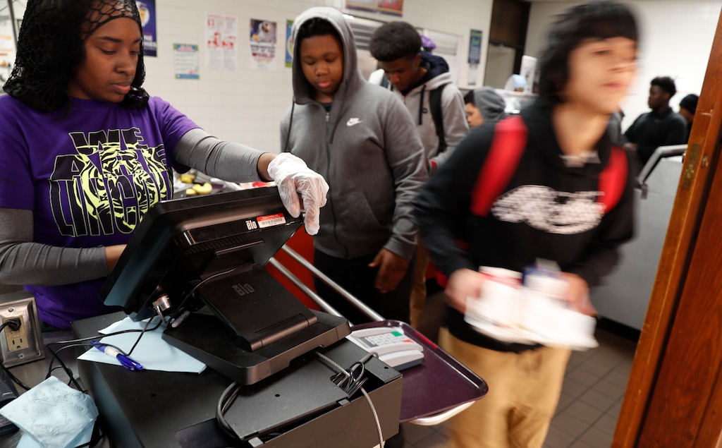 Students line up in the cafeteria for lunch at Lincoln High School in Dallas, Friday, March 13, 2020. During the coming extended spring break school closures, this cafeteria and a few others in the Dallas Independent School District will be providing lunches to students despite the closure of the school. (AP Photo/LM Otero)
