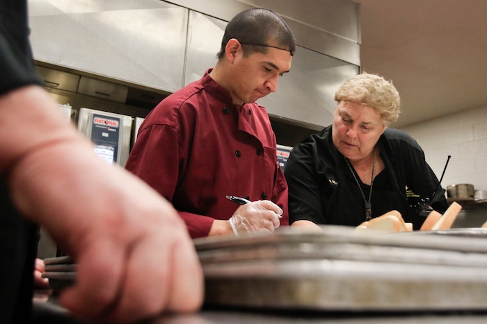 In this photo taken Jan. 26, 2018, Andres Torres works with civilian cook Susan Woods in the Utah County Jail's kitchen in Spanish Fork, Utah. The Utah County Jail Culinary Arts program utilizes inmates labor in the commercial kitchen. (Evan Cobb/The Daily Herald via AP)