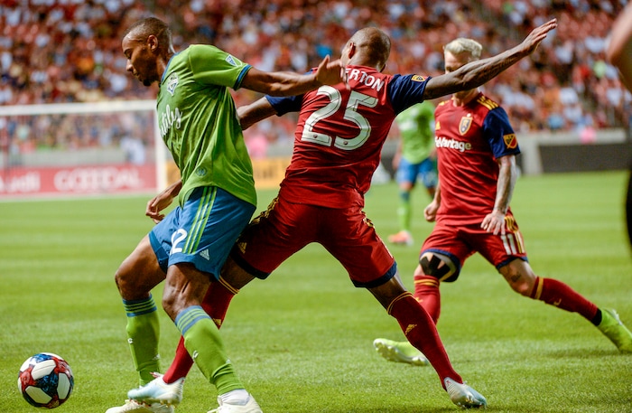 (Leah Hogsten  |  The Salt Lake Tribune) Seattle Sounders defender Saad Abdul-Salaam (12) hits the pitch while battling Real Salt Lake midfielder Everton Luiz (25) for possession as Real Salt Lake hosts the Seattle Sounders, Aug. 14, 2019, at Rio Tinto Stadium in Sandy. RSL defeated the Sounders 3-0.