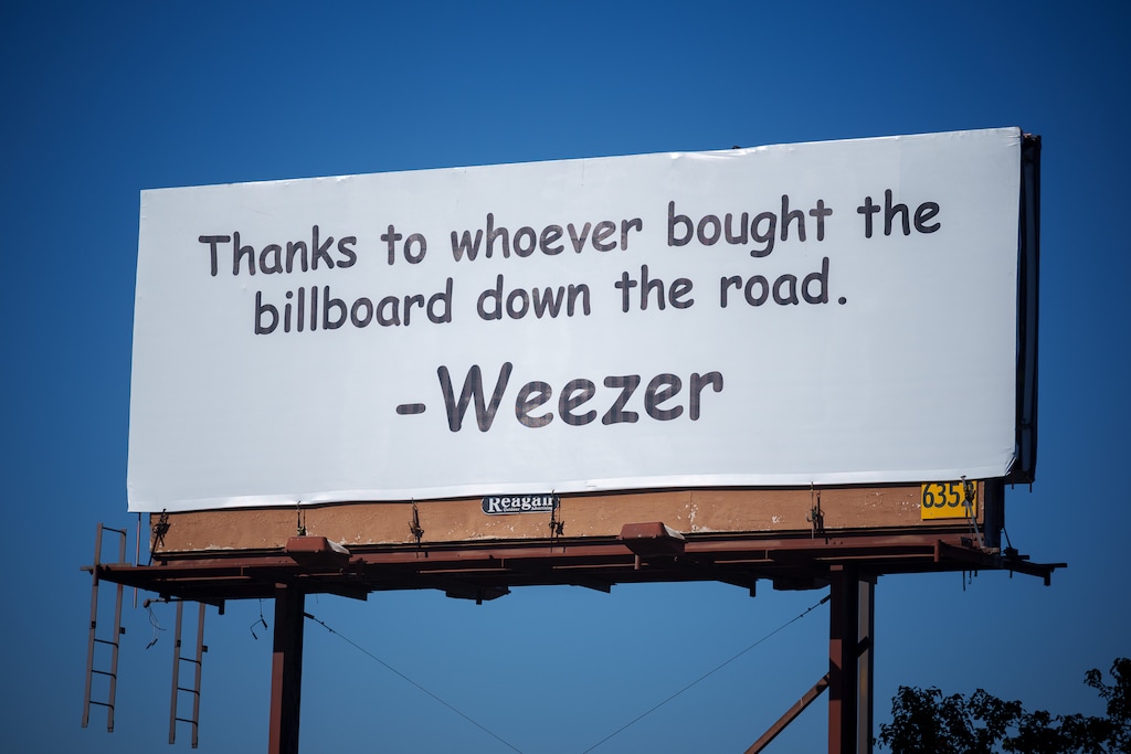 (Trent Nelson | The Salt Lake Tribune) A billboard on State Street that cropped up in Murray this week, apparently in response to a different billboard that showed up in June, about a half-mile away on State Street, that just read, "WEEZER," paid for by Utah-based social media content creator Cory Hunter Winn and his company. It seems the newest billboard, shown here on Friday, Oct. 14, 2022, came directly from the band.