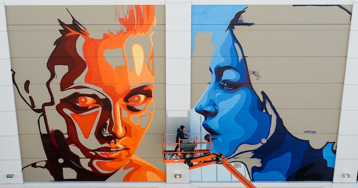 (Francisco Kjolseth  |  The Salt Lake Tribune)  Mural artist Fabio Lopez Gonzalo, aka Dourone, continues work on a large piece on the Clark Planetarium wall entitled "Two World Faces" on Tuesday, Oct. 10, 2017. Dourne, who started out as a mural artist in Spain, and other internationally renowned artists are creating art installations at The Gateway in downtown Salt Lake City in an effort to transform the public art landscape.