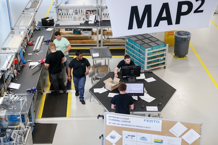 Apprentices stand at workstations at the automation learning center at the Festo distribution facility, Wednesday, May 17, 2017 in Mason, Ohio. Lou Morales, who trains the apprentices, understands the negative images associated with manufacturing. Years ago, he showed up at his steel mill at Glen Cove, New York, to find he no longer had a job after it shut down suddenly. "I've never seen so many padlocks in my life," recalled Morales, 60. But now he assures young people that "the future is endless" for them in manufacturing because new kinds of jobs are being created and the skills they are learning are in high demand. (AP Photo/John Minchillo)