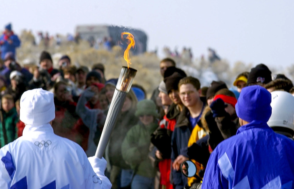 (Paul Fraughton  |  The Salt Lake Tribune) The air is thick with smog as the Olympic Torch passes a frozen throng of spectators on Antelope Island on Feb. 6, 2002.
