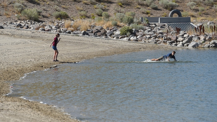 (Francisco Kjolseth  |  The Salt Lake Tribune)  Kennedy Stroud, 15, watches as Nathan Depew, 16, jumps into Black Ridge Reservoir in Herriman before being warned by other visitors about the warning signs posted at the popular recreation spot on Tuesday, Aug. 28, 2018, where an outbreak of algae-related toxin cyanobacteria was detected in the water.