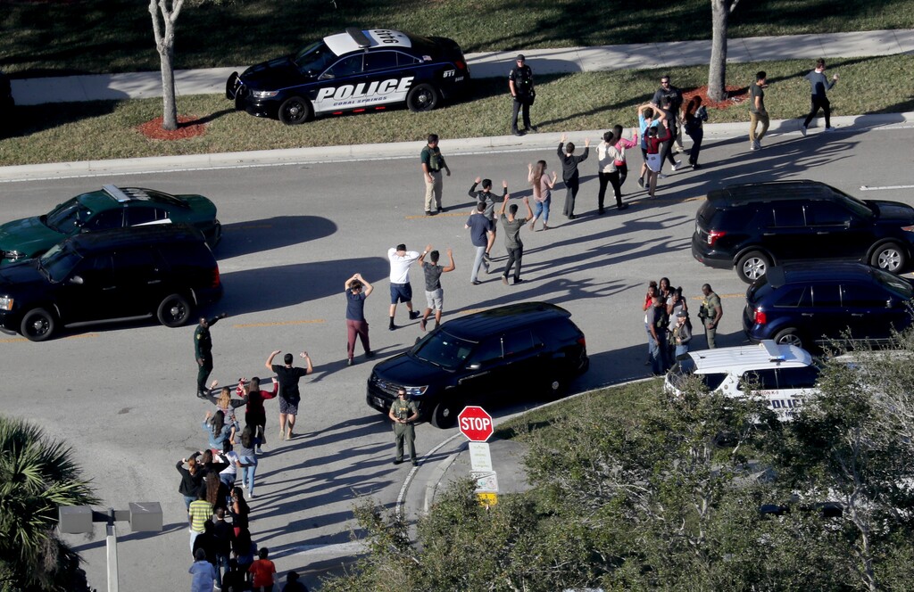 (Mike Stocker | South Florida Sun-Sentinel | The Associated Press) In this Feb. 14, 2018 file photo,  students hold their hands in the air as they are evacuated by police from Marjory Stoneman Douglas High School in Parkland, Fla., after a shooter opened fire on the campus.  Students are taught to evacuate during fire alarms but lock down during school shootings. So there was confusion Wednesday when a fire alarm sounded,  the second one that day at the high school as 19-year-old former student Nikolas Cruz unleashed a barrage of gunfire. Head for the exits or hunker down in classrooms?