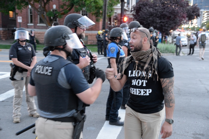 (Francisco Kjolseth  |  The Salt Lake Tribune) Matthew Byrd bumps fists with police after deescalating tensions by protesters remarking "we need to create change and reform not animosity and violence," as police line up to enforce a mandatory curfew in Salt Lake City on Monday, June 1, 2020.