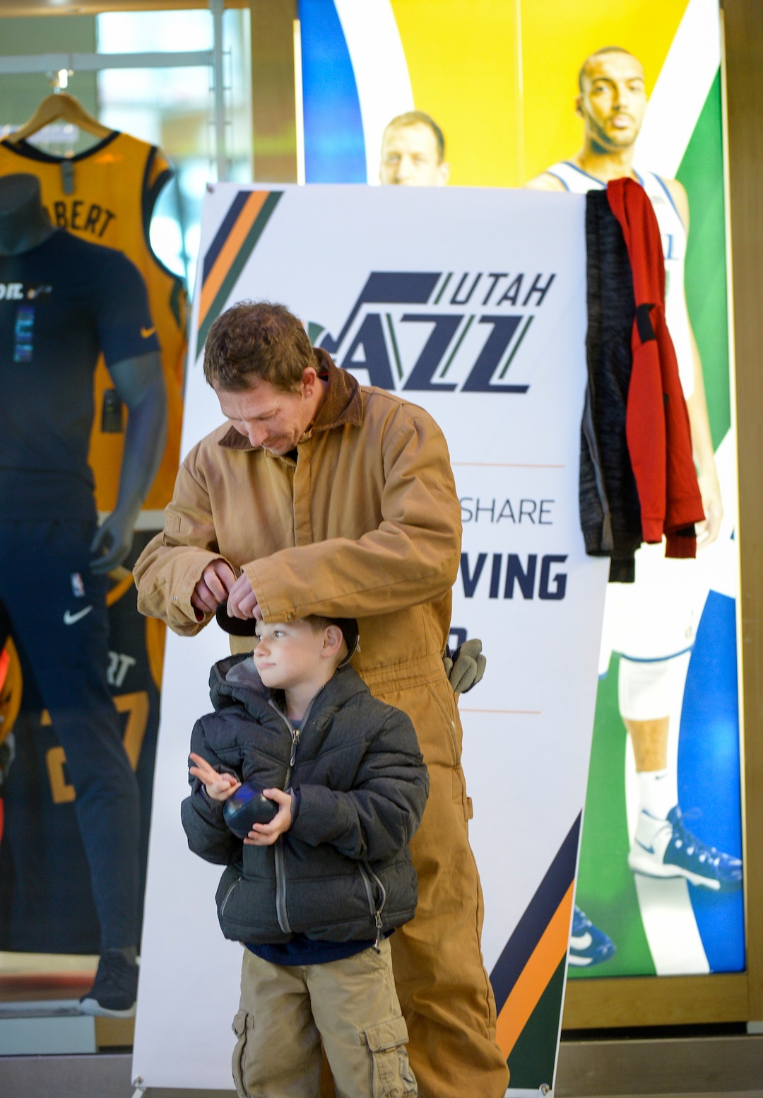 Leah Hogsten  |  The Salt Lake Tribune  Jason McCowen adjusts his son Elijah Hansen's new hat at the Utah Jazz and the Larry H. Miller Group sponsored annual “We Care – We Share” Thanksgiving Meal for local homeless and low-income families, Monday, Nov 19, 2018.