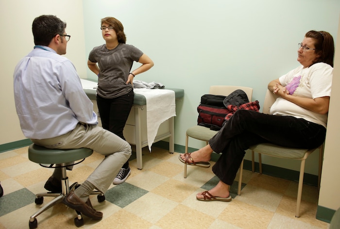 (Lynne Sladky | The Associated Press) In this Thursday, Oct. 8, 2015 photo, Theo Ramos, 14, center, talks with endocrinologist Dr. Alejandro Diaz, center, accompanied by his mother, Lori, in Miami. Doctors say going slow when treating trans teens is essential for their physical and emotional well-being, and note that if a teen’s feelings last until age 16, their desires are probably permanent.