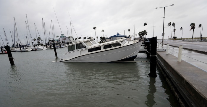(Eric Gay | The Associated Press) A fishing boat is left partial submerged after Hurricane Harvey swept through the area, Saturday, Aug. 26, 2017, in Corpus Christi, Texas. Harvey has been further downgraded to a Category 1 hurricane as it churns slowly inland from the Texas Gulf Coast, already depositing more than 9 inches of rain in South Texas.