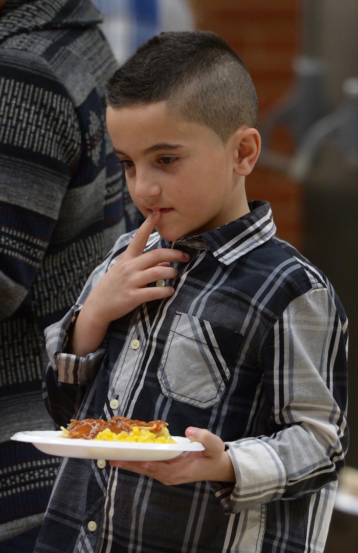 (Leah Hogsten  |  The Salt Lake Tribune) Ibrahim Sadiq, 8, decides what he wants from servers. Sixteen members of Granite Park Junior High SchoolÕs faculty prepared and served a hot spaghetti meal to students and their families, Friday, December 22, 2017 at the school for the inaugural ÔDinner at the Park.' Roughly 90 percent of students who attend Granite Park Junior High in South Salt Lake qualify for free or reduced lunch through the federal school lunch program. Knowing the challenges faced by their students, staff members at Granite Park came up with an idea to help families through the holidays.