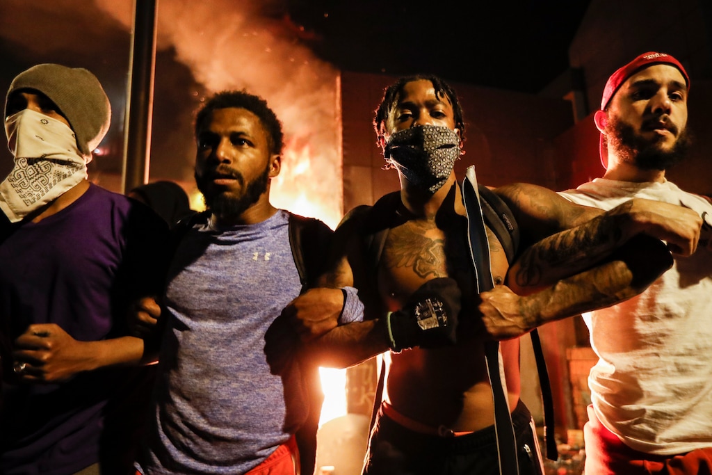 Protestors demonstrate outside of a burning Minneapolis 3rd Police Precinct, Thursday, May 28, 2020, in Minneapolis. Protests over the death of George Floyd, a black man who died in police custody Monday, broke out in Minneapolis for a third straight night. (AP Photo/John Minchillo)