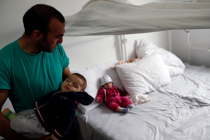 Hamad Ahmadi's brother holds his child in the "Krnjaca" centre for asylum seekers near Belgrade, Serbia, Monday, Sept. 18, 2017. The European Union border that saw hundreds of thousands of migrants enter freely in 2015 has since become a sealed fortress with two rows of fence and closed border camps that the United Nations have described as “in effect detention centers.” (AP Photo/Darko Vojinovic)