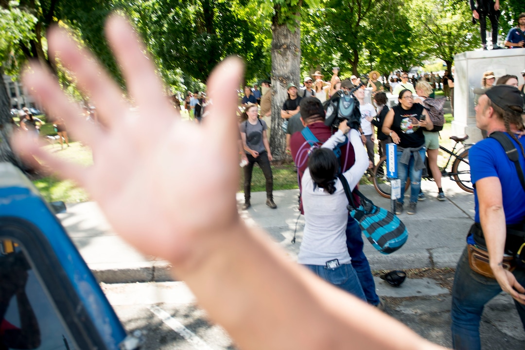 (Jeremy Harmon |  The Salt Lake Tribune) A person tries to block a Tribune photographer from photographing a woman as she tries to pull a camera away from a news photographer following an inland port protest on Tuesday, July 9, 2019.