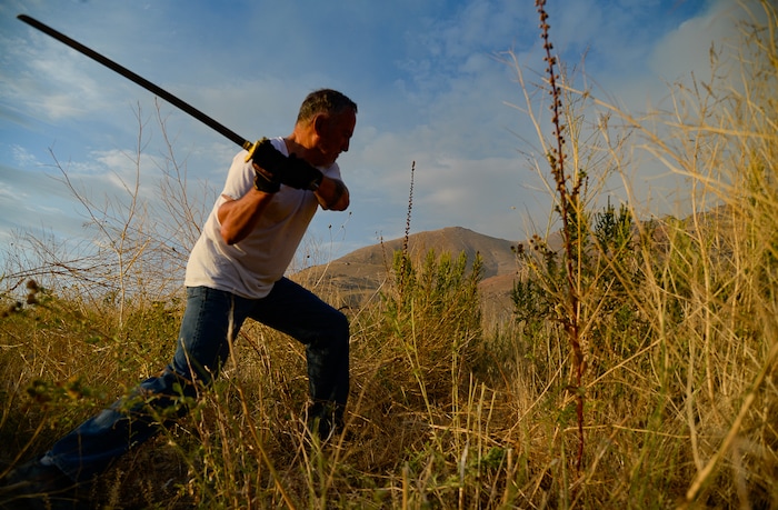 (Francisco Kjolseth  |  The Salt Lake Tribune)  Kelin Brito uses any tool at his disposal as he cuts down tall brush with a samurai sword given to him as a gag gift by his son as the community comes together to join crews battling a grass fire in Tooele county being dubbed the Green Ravine fire as it burns on Tuesday, Sept. 3, 2019.