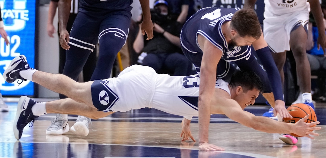 (Francisco Kjolseth | The Salt Lake Tribune) Brigham Young Cougars guard Alex Barcello (13) goes down as Utah State Aggies forward Brandon Horvath (4) moves in basketball action between the Brigham Young Cougars and the Utah State Aggies at the Marriott Center in Provo, Wednesday, Dec. 8, 2021.