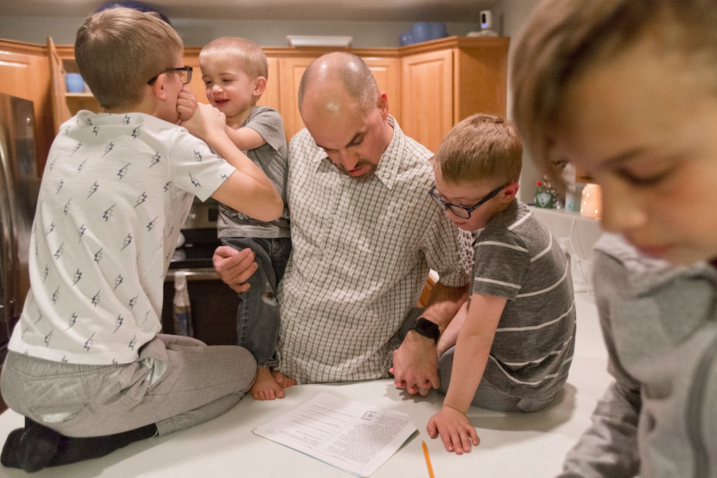 (Evan Cobb /The Daily Herald via AP) Devin Goulding, center, helps his son, McKay, 7, second from right, with his homework in their family's kitchen on Monday, Feb. 11, 2019, in Orem, Utah. . Devin and Erica Goulding have six kids. Their oldest, Blake, is 12 and their youngest, Emery, is 3-months-old. Families with six kids or more are becoming more unusual nationally, as fertility rates drop and women begin having children at an older age than they traditionally have.