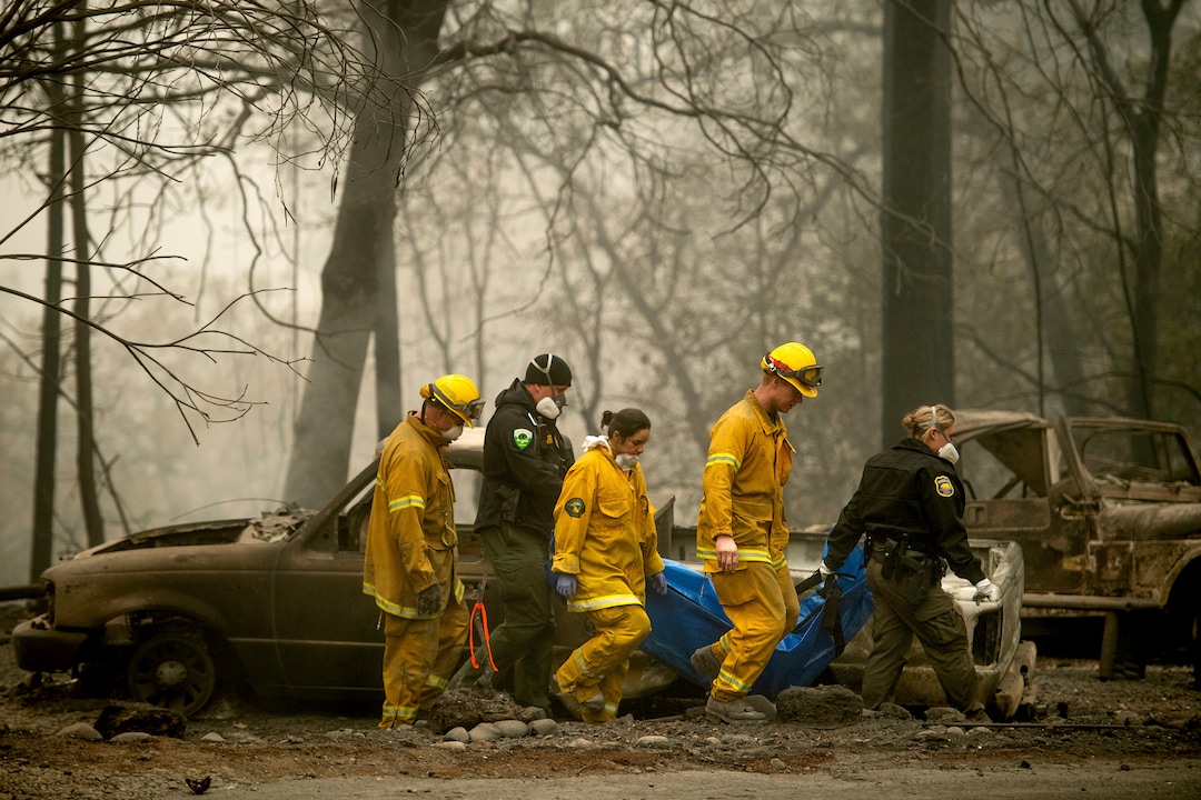 Firefighters recover the body of a Camp Fire victim at the Holly Hills Mobile Estates on Wednesday, Nov. 14, 2018, in Paradise, Calif. Thousands of homes were destroyed when flames hit Paradise, a former gold-mining camp popular with retirees, on Nov. 8, killing multiple people in California's deadliest wildfire. (AP Photo/Noah Berger)