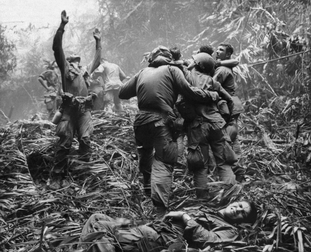 (Art Greenspon | AP file photo) This April 1968 photo shows the first sergeant of A Company, 101st Airborne Division, guiding a medevac helicopter through the jungle foliage to pick up casualties suffered during a five-day patrol near Hue, April 1968. Two soldiers in the photo, Dallas Brown, bottom, and Tim Wintenburg, far right, recently reunited to talk to The Associated Press about the iconic photo and the war.