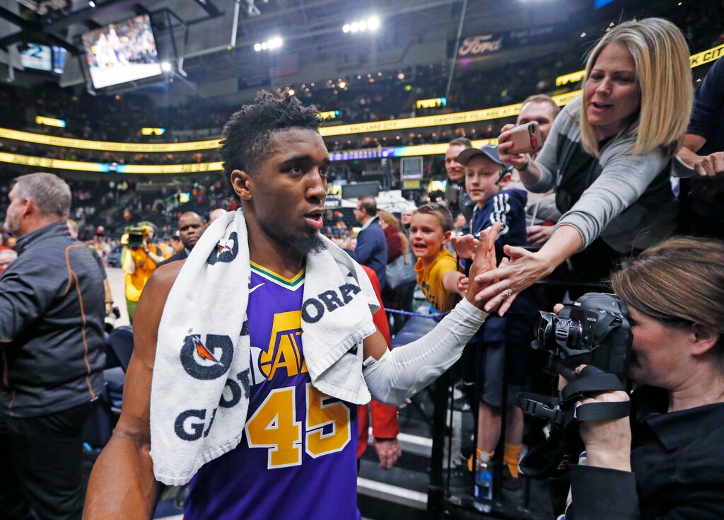 A fan reaches for Utah Jazz guard Donovan Mitchell (45) as he walks off the court following the team's NBA basketball game against the Orlando Magic on Wednesday, Jan. 9, 2019, in Salt Lake City. (AP Photo/Rick Bowmer)