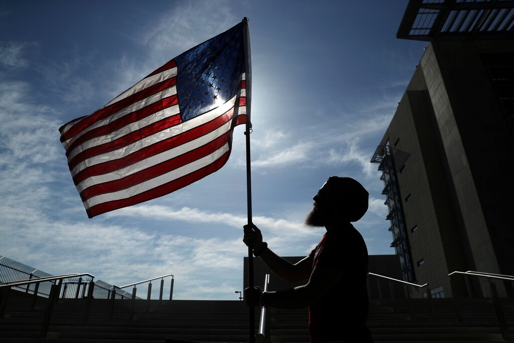 FILE - In this April 10, 2017 file photo, a protester holds up a flag outside of a federal courthouse in Las Vegas in support of defendants accused of wielding weapons against federal agents during a 2014 standoff involving cattleman and states' rights advocate Cliven Bundy. A federal jury in Las Vegas is deliberating again Monday, Aug. 21, 2017, in the retrial of four men accused of wielding assault weapons against federal agents in a 2014 standoff near the Nevada ranch of anti-government figure Cliven Bundy. Jurors returned to work Monday, after spending a little more than two days last week going over five weeks of evidence in the case against four defendants. (AP Photo/John Locher, File)
