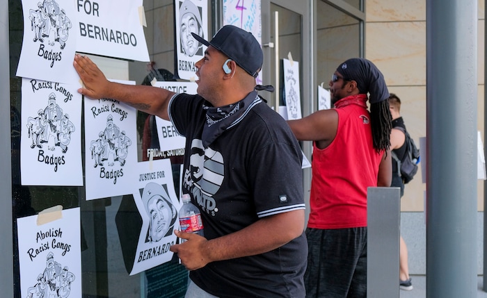 (Leah Hogsten  |  The Salt Lake Tribune) Mani Hill and fellow protesters tape flyers to the West Valley Police Department building during the People's Council rally to defund the police force, Aug.8, 2020. Over a dozen of police officers dressed in riot gear could be seen standing inside the building. Saturday's rally was hosted by the Salt Lake chapter of the Party for Socialism and Liberation.