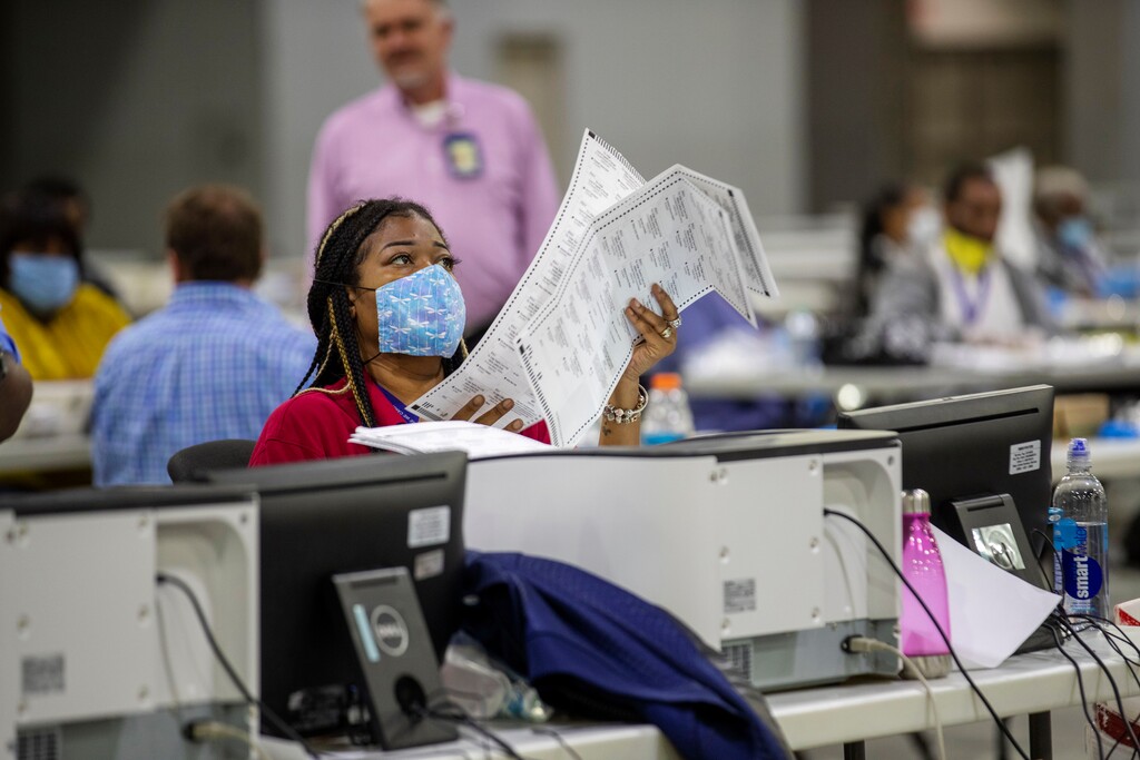 (Alyssa Pointer | Atlanta Journal-Constitution via AP file photo) Fulton County employee Shaye Moss scans mail-in paper ballots at the Georgia World Congress Center during the Georgia primary elections in Atlanta on Tuesday, June 9, 2020.