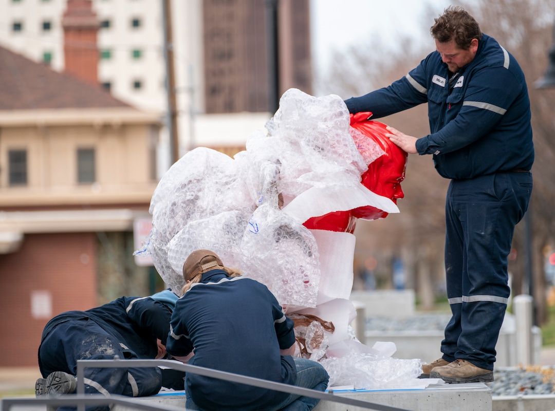 (Rick Egan | The Salt Lake Tribune)  Workers place a new art installation featuring a life-size sumo wrestler, in front of the Mountain West Commercial Real Estate building, previously the KALL Radio 910 broadcast station, on South Temple, in Salt Lake City, on Monday, March 29, 2021