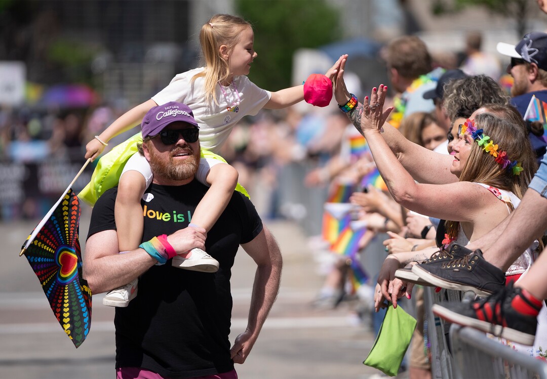 (Rick Egan | The Salt Lake Tribune)  Olivia Winn, high-fives spectators on the shoulders of her dad, Travis Winn , in the Pride Parade, on Sunday, June 4, 2023.