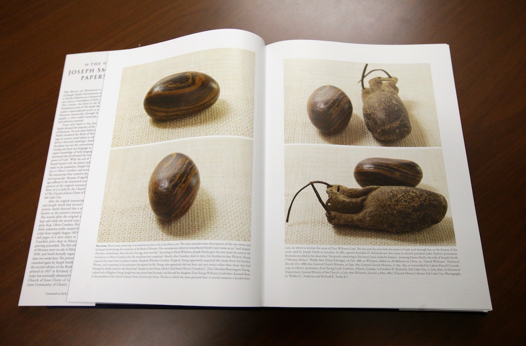 Pictures of a smooth, brown, egg-sized rock are shown in the printer's manuscript of the Book of Mormon following a news conference Tuesday, Aug. 4, 2015, at the Church of Jesus Christ of Latter-day Saints Church History Library, in Salt Lake City. The Mormon church for the first time is publishing photos of a small sacred stone it believes founder Joseph Smith used to help translate the story that became the basis of the religion. The Mormon church is taking another step in its push to be more transparent, and is releasing more historical documents that shed light on how Joseph Smith formed the religion. (AP Photo/Rick Bowmer)