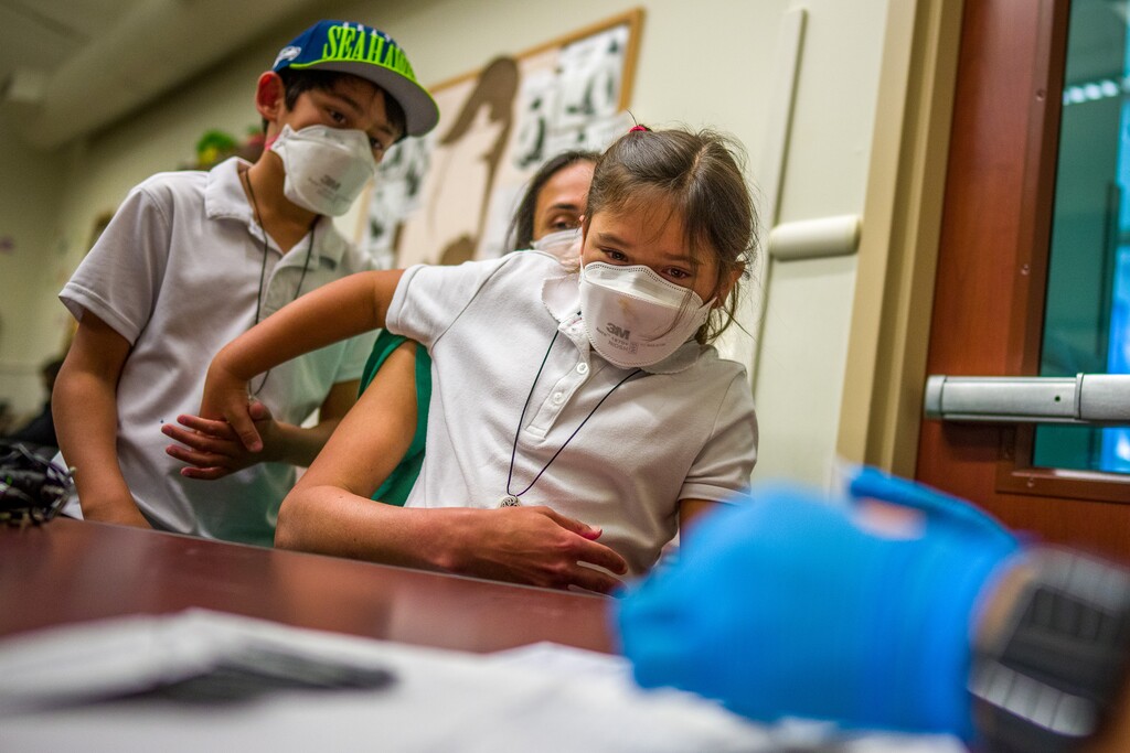 Arya Martinez sits on the lap of her mother, Dr. Amrapali Shah, and holds her brother Kirav's hand as she is vaccinated against COVID-19 by Tenzin Drongsar at South Main Public Health Center in South Salt Lake on Wednesday, Nov. 3, 2021.