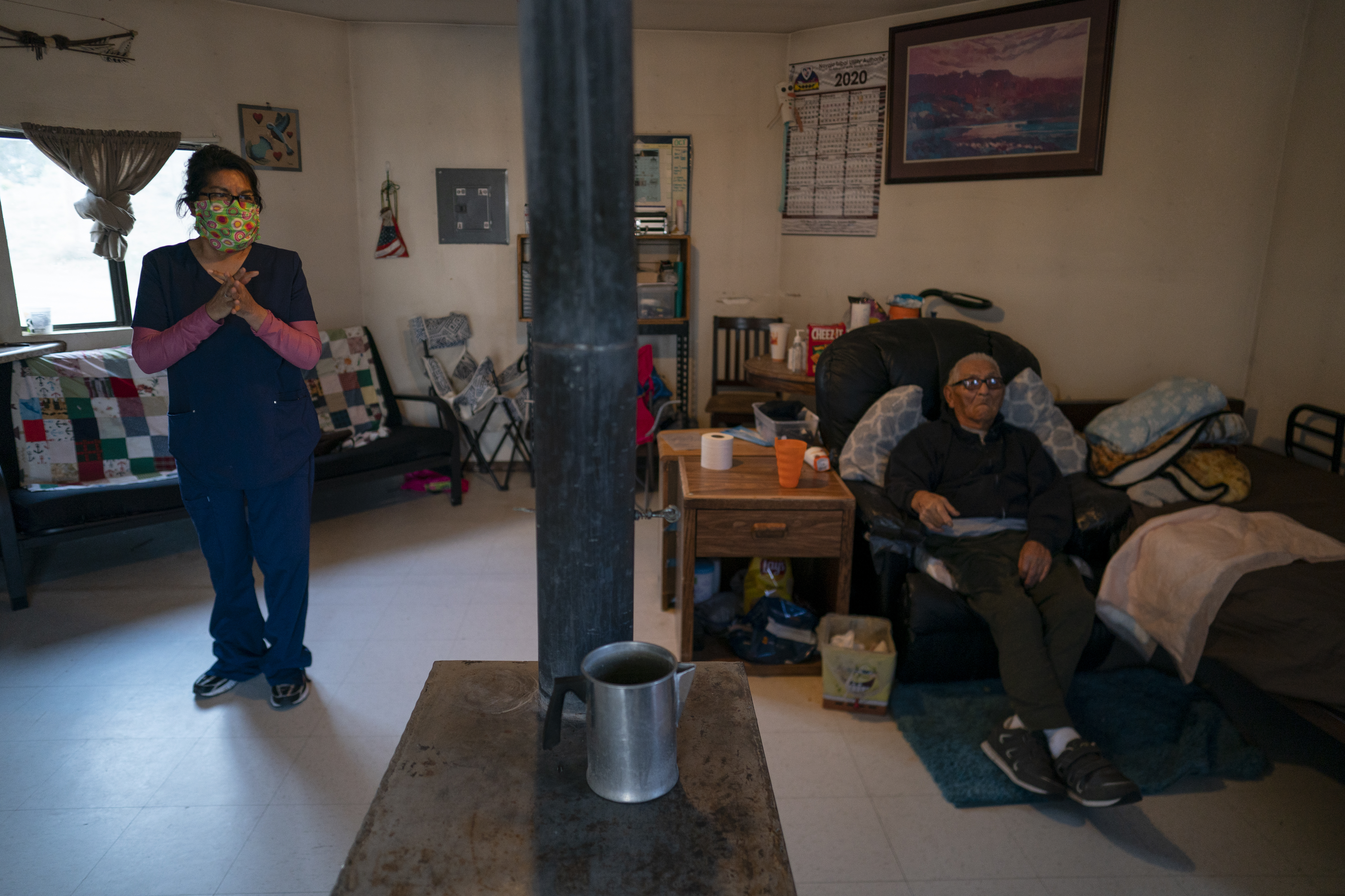 (Carolyn Kaster | AP) Mabel Charley, left, applies hand sanitizer as she arrives to care for her home-bound uncle in his hogan, a traditional Navajo dwelling, in Chilchinbeto, Ariz., on the Navajo reservation on April 21, 2020. The Navajo reservation has some of the highest rates of coronavirus in the country. If Navajos are susceptible to the virus' spread in part because they are so closely knit, that's also how many believe they will beat it.