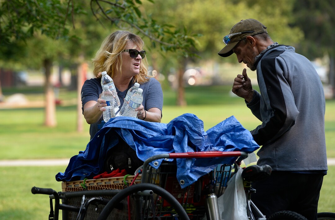(Scott Sommerdorf   |  The Salt Lake Tribune)   Machele Nieto, of the Volunteers of America, hands out water and some supplies to a homeless man in Fairmont Park, Wednesday, September 6, 2017.