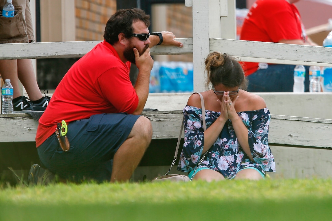 A woman prays in the grass outside the Alamo Gym where parents wait to reunite with their kids following a shooting at Santa Fe High School Friday, May 18, 2018, in Santa Fe, Texas. (Michael Ciaglo/Houston Chronicle via AP)