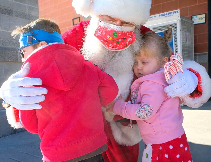 (Leah Hogsten  |  The Salt Lake Tribune)  Siblings Memphis Miller, 3, and Savannah, 3, get a hug from Old Saint Nick at Macey's grocery store on Thursday. The jolly fat man also greeted Macey's guests who scheduled a grocery pickup time, Dec. 24, 2020.