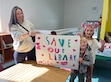 (Brynnan Sainsbury | Cache County Library) Cache County resident Mary Jo Duersch and her two children hold up a “Save Our Library” sign at the Cache County Library's letter signing event on Oct. 11, 2025.