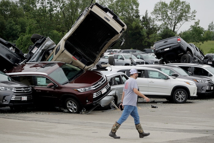 (Charlie Riedel |AP) A worker walks past tornado-damaged Toyotas at a dealership in Jefferson City, Mo., Thursday, May 23, 2019, after a tornado tore though late Wednesday.