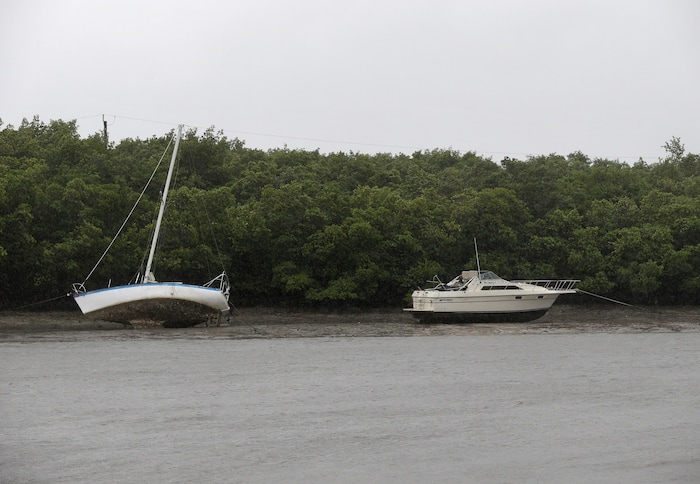 (AP Photo/Gerald Herbert) Two boats that are moored sit in mud due to an unusually low tide, as the first effects of Hurricane Irma reach Fort Myers, Fla., Sunday, Sept. 10, 2017. Announcing itself with roaring 130 mph winds, Hurricane Irma plowed into the mostly emptied-out Florida Keys early Sunday.