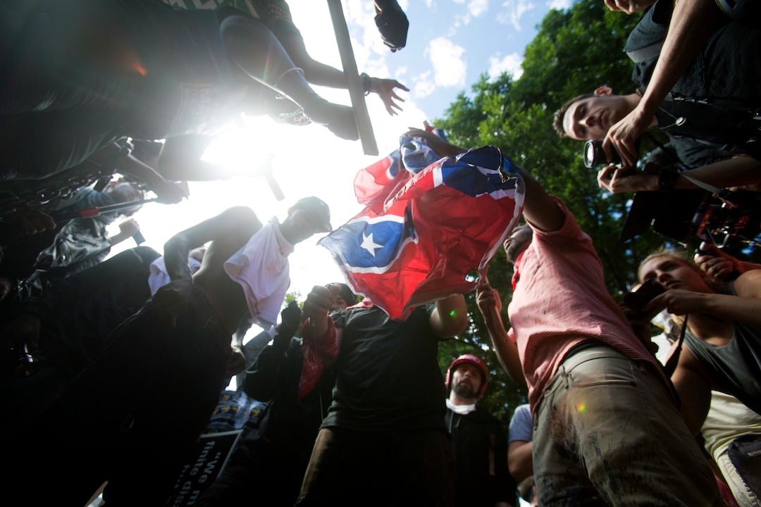 Counter-protesters tear a Confederate flag during a white nationalist rally, on Saturday Aug. 12, 2017, in Charlottesville, Va.  (Shaban Athuman /Richmond Times-Dispatch via AP)