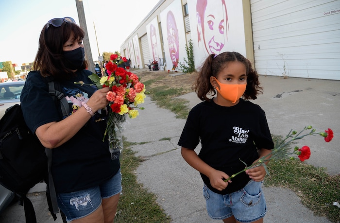 (Francisco Kjolseth  |  The Salt Lake Tribune) Ann Lovato is joined by her granddaughter Nyssa King, 9, as they place flowers by the portraits of those killed by police near 800 South and 300 West in Salt Lake City on Tuesday, August 11, 2020. Multiple families who’s loved one’s are depicted on the walls joined a vigil initially organized to recognize Dillon Taylor who was killed 6-years ago by a Salt Lake City police officer.