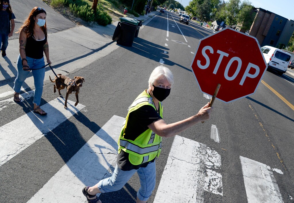 (Francisco Kjolseth | The Salt Lake Tribune) Christy Smith who has been a crossing guard for 33-years at Parkside Elementary in Murray, helps students and their parents cross Vine Street safely in Murray for the first day of school on Monday, August, 17, 2020. Murray is the first school district in the state to open.