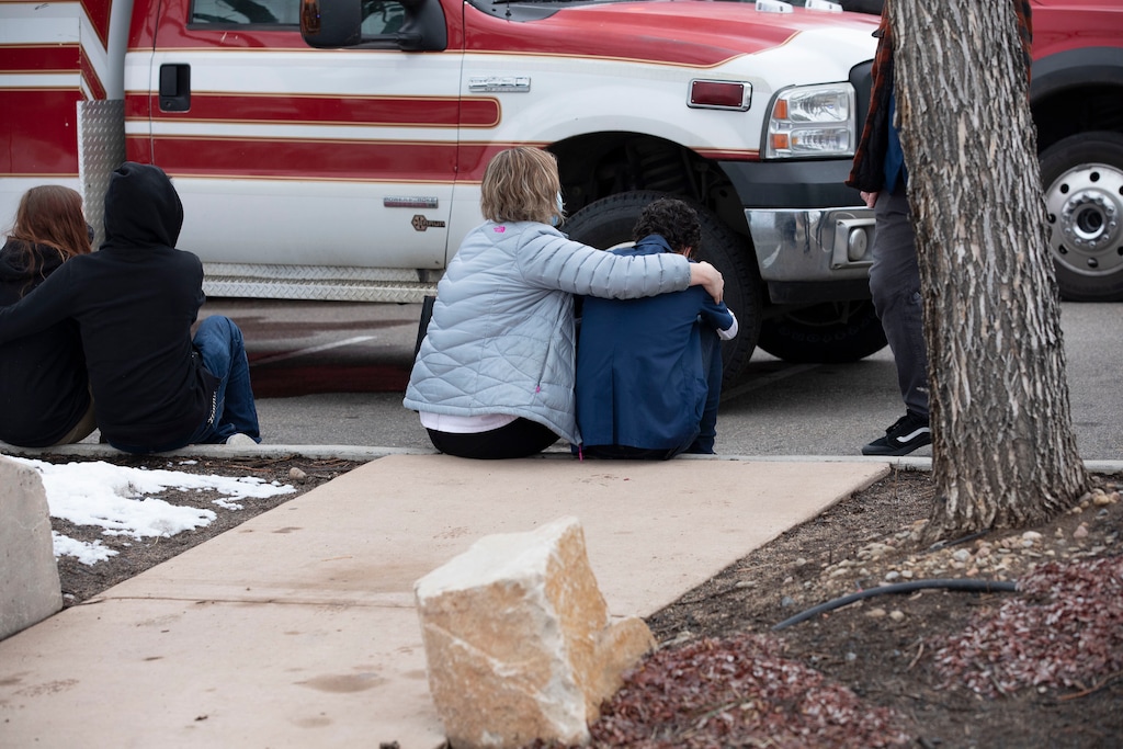 (Eliza Earle | The New York Times) People comfort each other outside of the Boulder King Soopers grocery store after a shooting that killed multiple people in Boulder, Colo., on Monday, March 22, 2021.