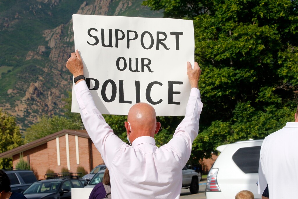 In this Monday, June 15, 2020, photo, a man gathers with others to publicly express support of local police in Cottonwood Heights, Utah. A pair of rallies on Monday drew one group calling for police reform and another voicing support for law enforcement. Demonstrators calling themselves "Cottonwood Heights Citizens for Law Enforcement and Peace Officers" held their rally right before the reform demonstration and handed out leaflets advocating against cutting police funding. (AP Photo/Rick Bowmer)