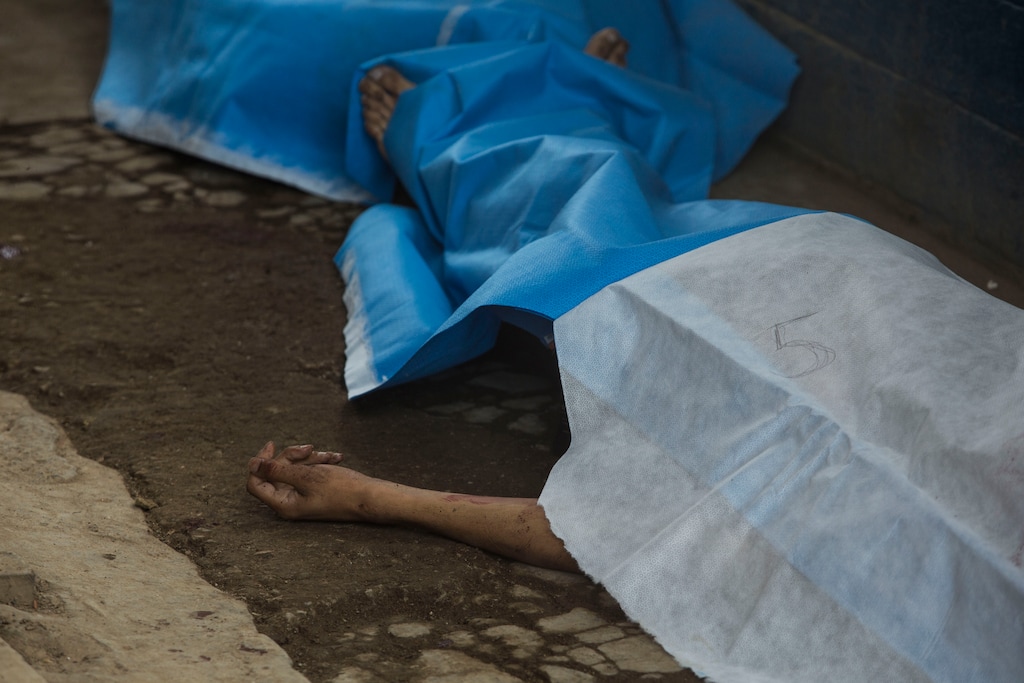 Covered bodies lie inside the entrance area of the Pavon Rehabilitation Model Farm after a shooting inside the jail in Fraijanes, Guatemala, Tuesday, May 7, 2019. Gunfire during a riot in a Guatemala prison Tuesday left at least seven inmates dead and 10 wounded, authorities said. (AP Photo/Oliver De Ros)