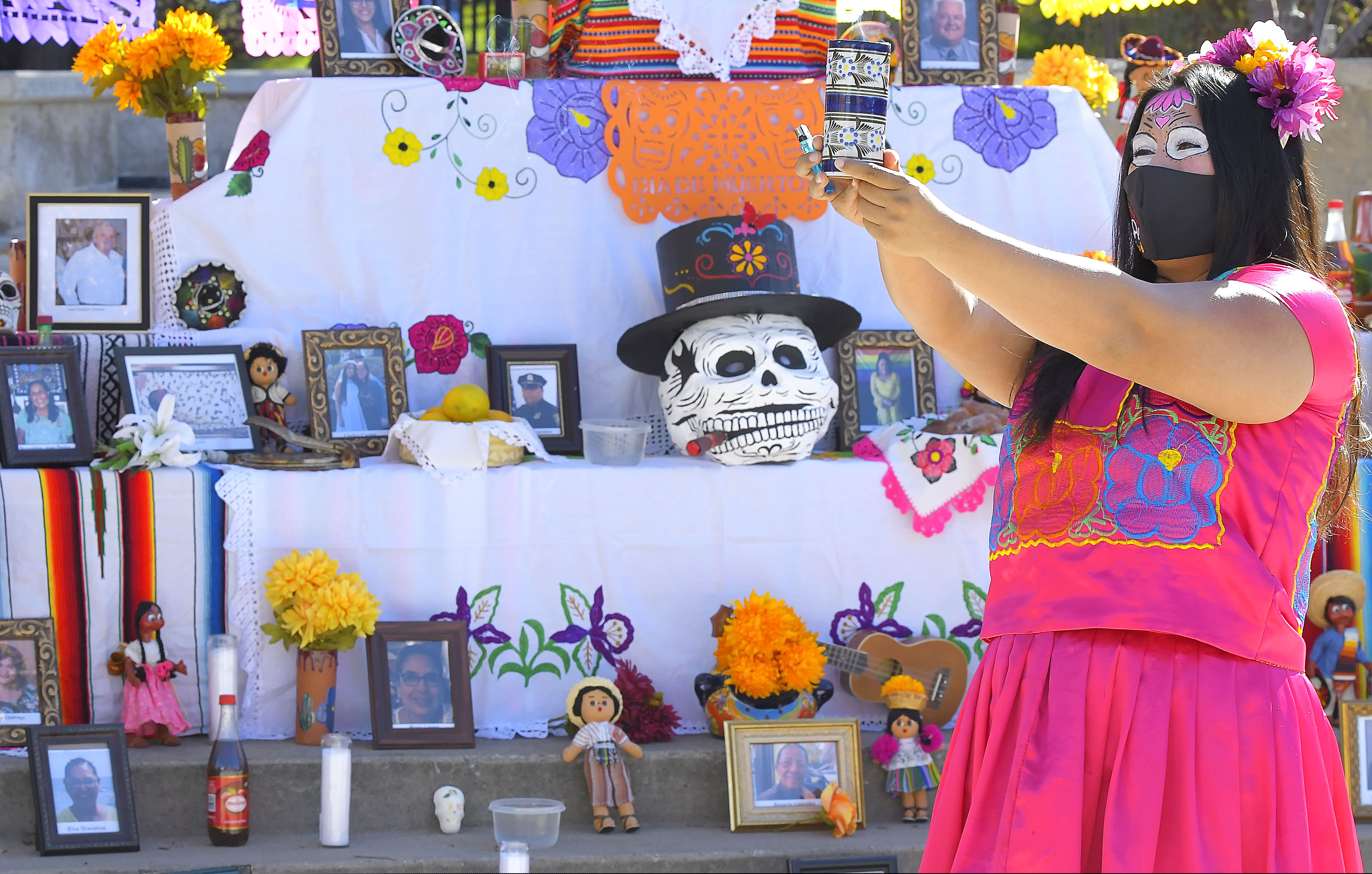 (Eli Lucero | The Herald Journal via AP) Lizette Villegas performs a blessing on an Ofrenda for those who died of COVID-19, as part of Día de Muertos celebration on Monday, Nov. 2, 2020, in Logan.