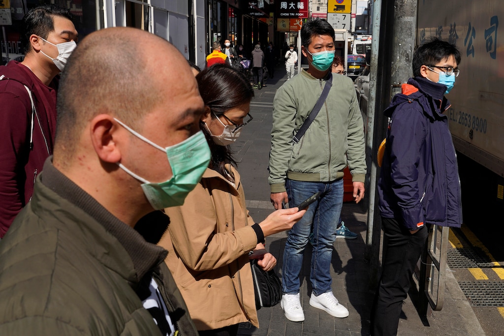 (Vincent Yu | The Associated Press) People wearing face masks walk on a down own street in Hong Kong Friday, Feb. 21, 2020. COVID-19 viral illness has sickened tens of thousands of people in China since December.