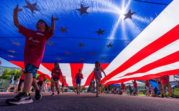 (Rick Egan | The Salt Lake Tribune) Marchers carry a giant American Flag, in the Cherry Days Forth of July Parade, in North Ogden, on Monday, July 4, 2022.
